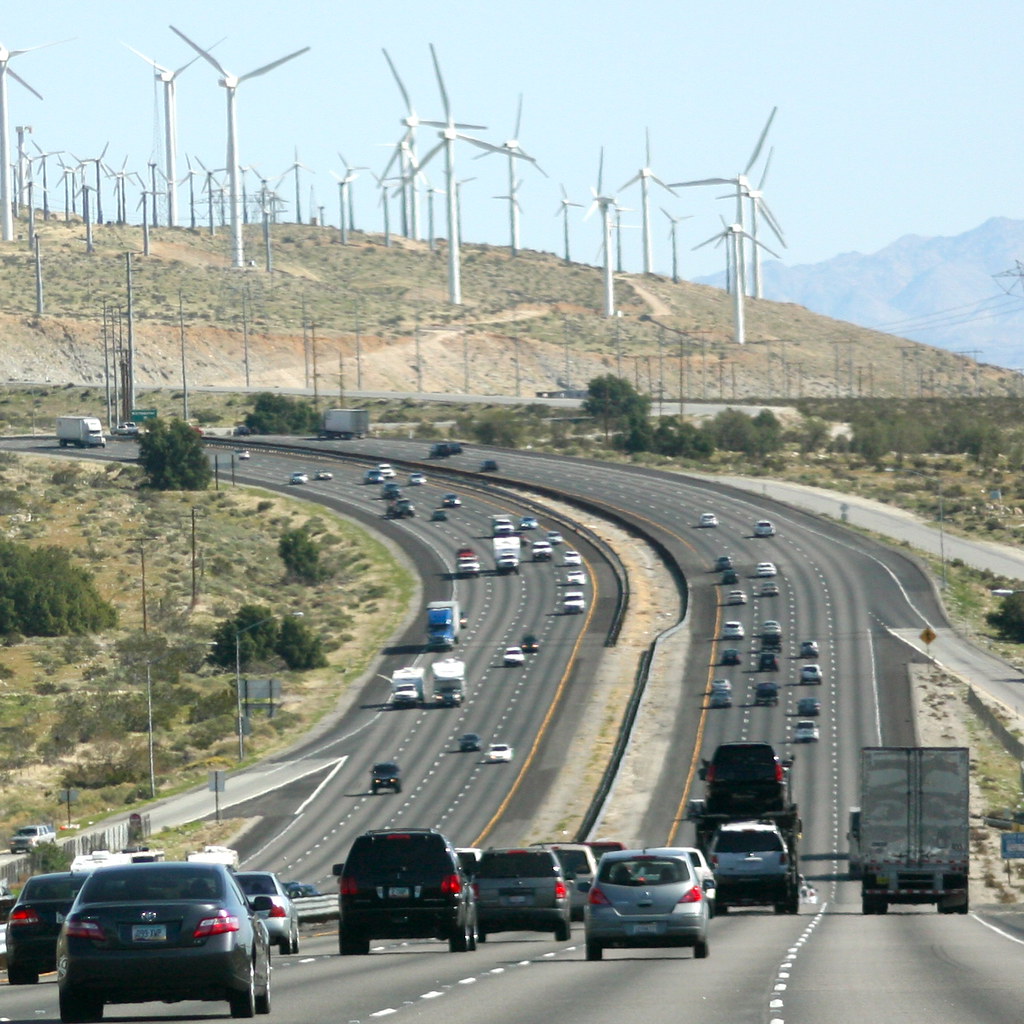 Cars on freeway in foreground, wind turbines in distance