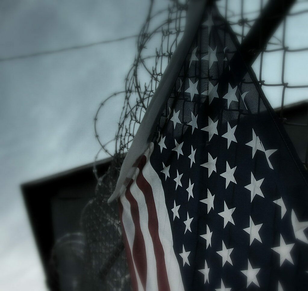 American flag draped from a fence with razor wire