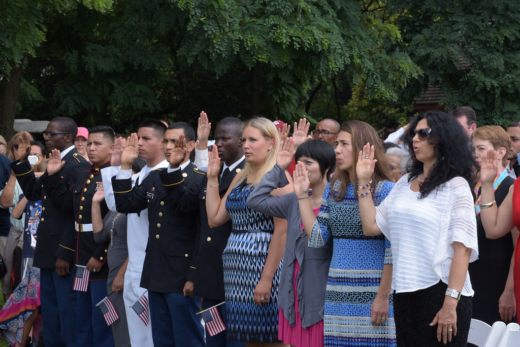 A diverse group of men and women take the oath of citizenship at a naturalization ceremony.