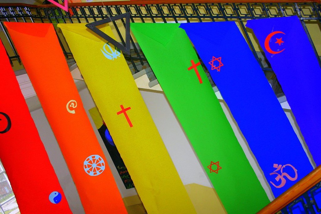 A series of banners in rainbow colors feature symbols from different religions