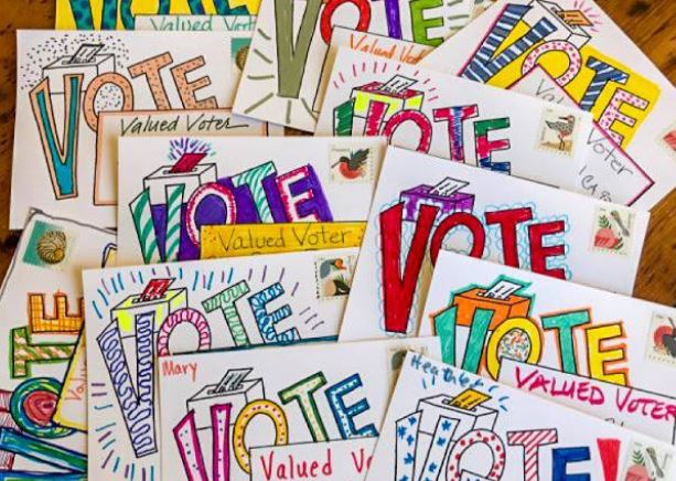 A stack of colorful handwritten postcards to voters, urging them to get out and vote