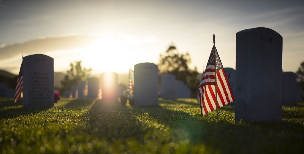Dawn breaks over a veterans cemetery with American flags planted at each headstone