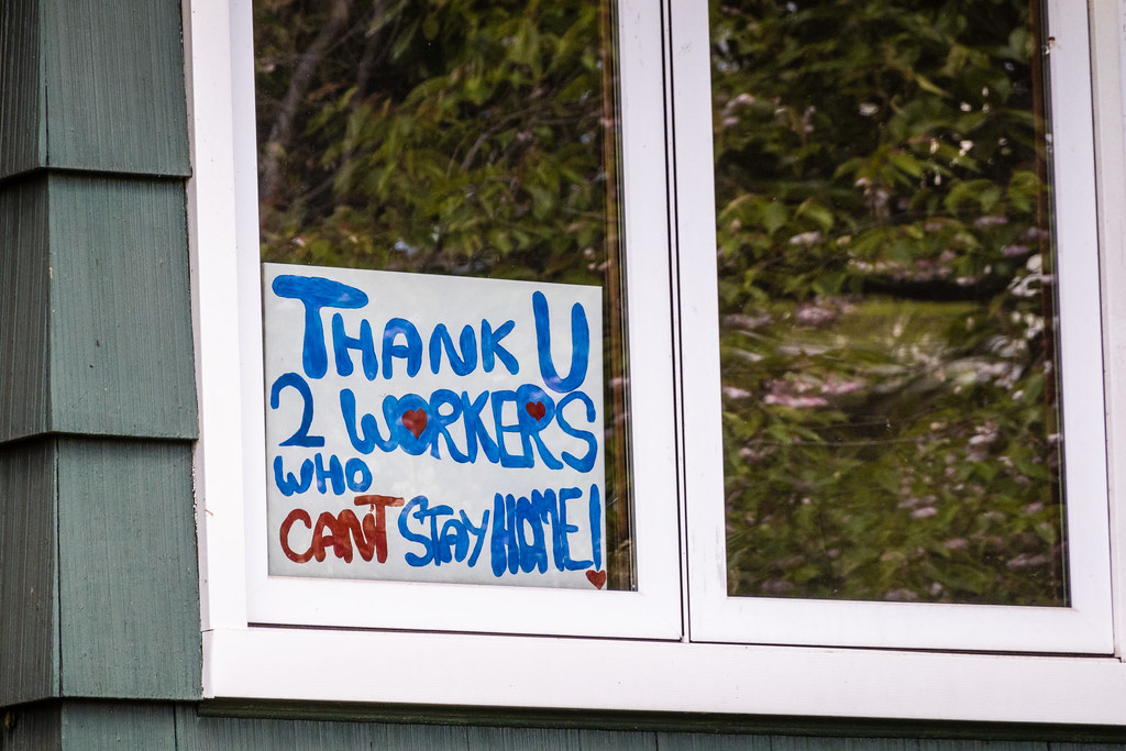 Handpainted sign in window of house reads, "Thank U 2 workers who can't stay home!"