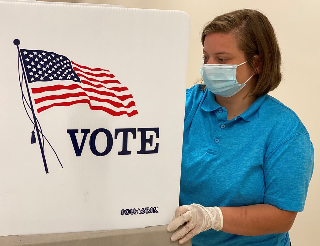 Woman in mask standing at a voting booth