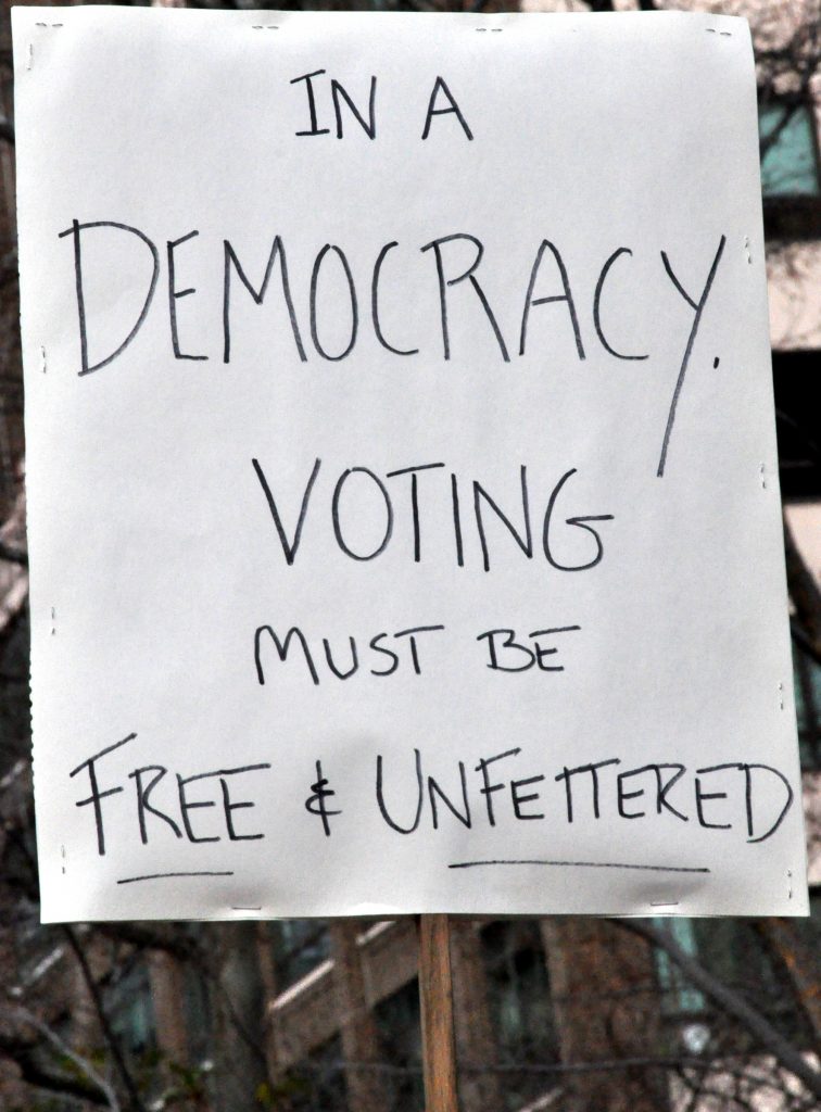 Sign of a protester which reads 'In a Democracy, voting must be free and unfettered"