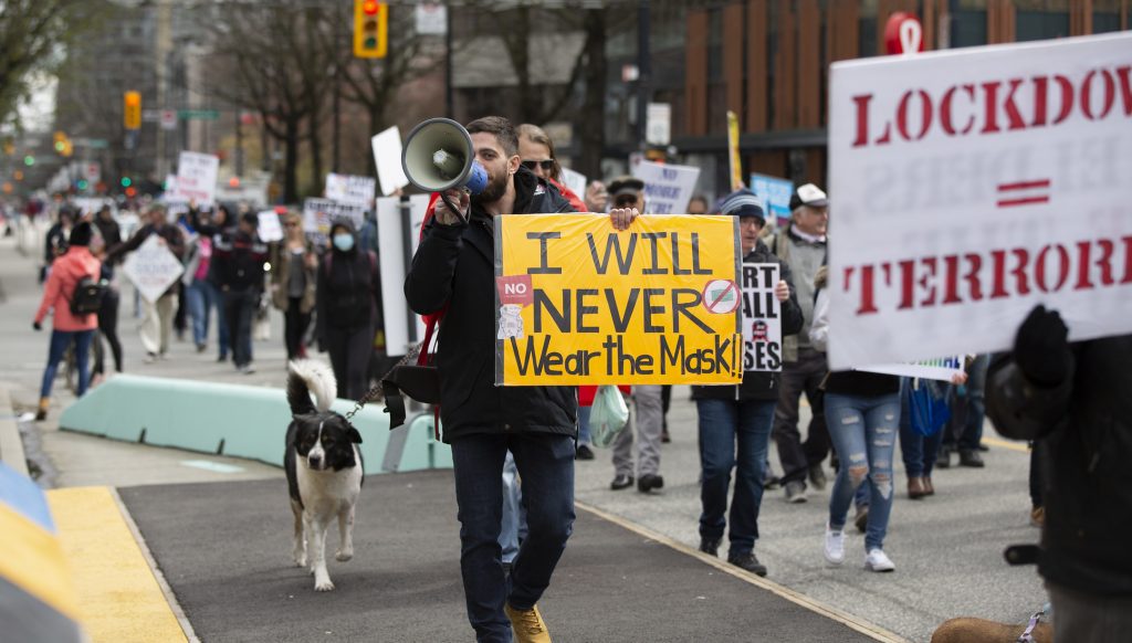 Anti-mask protest. Man with a sign which reads "I will never wear the mask!!"