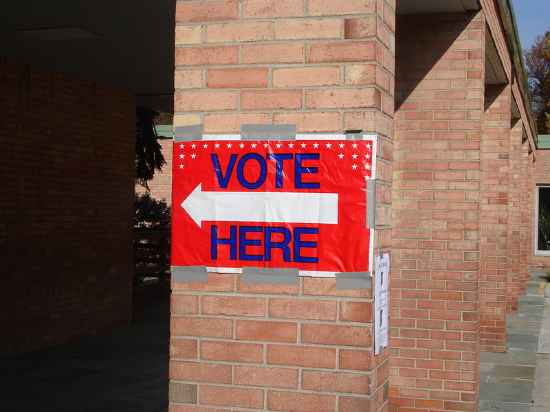 Vote here sign on a brick column