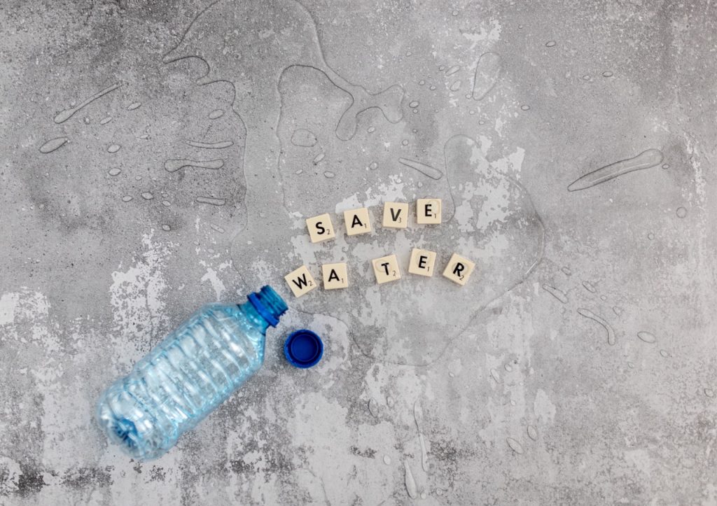 Plastic bottle with letters spilling out that spell "Save Water"