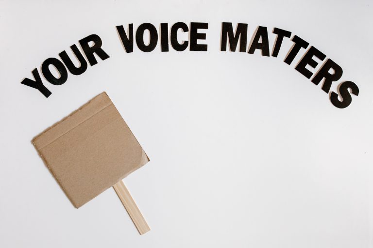 "Your Voice Matters" text with blank cardboard sign