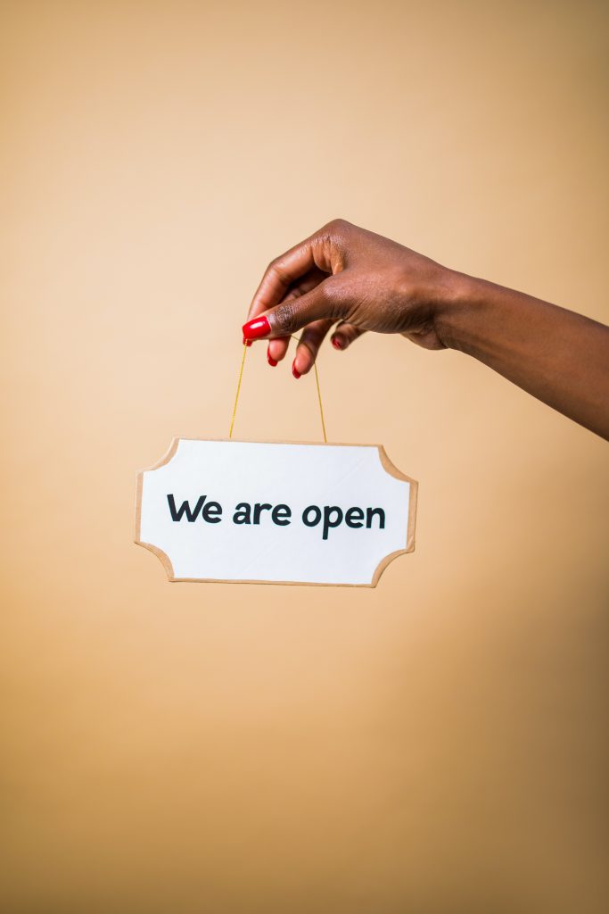 Hand holding up a "We are open" sign