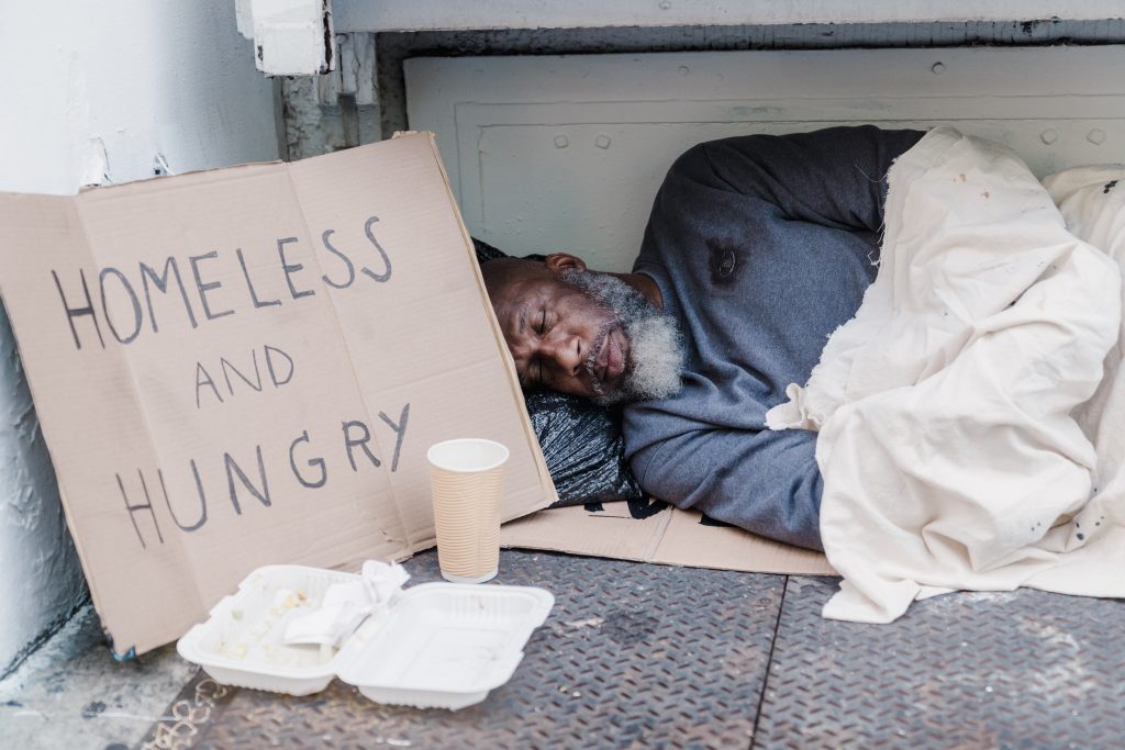 Man asleep on street with sign