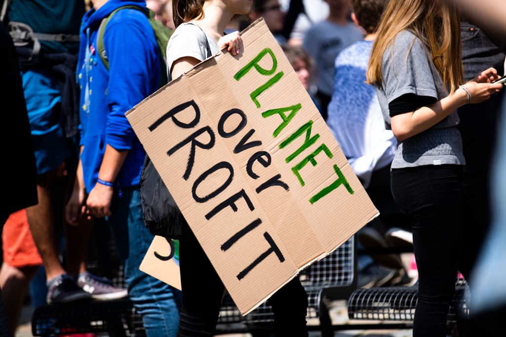 Protestor holding sign with words "Planet over Profit".