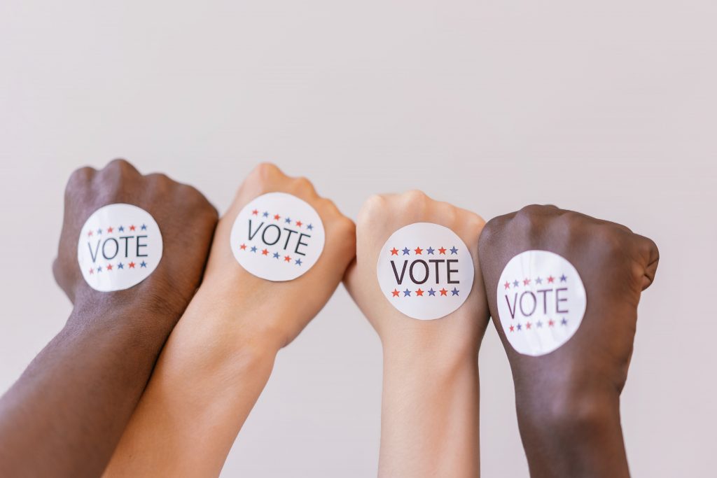 Close up of vote stickers on 4 fists.