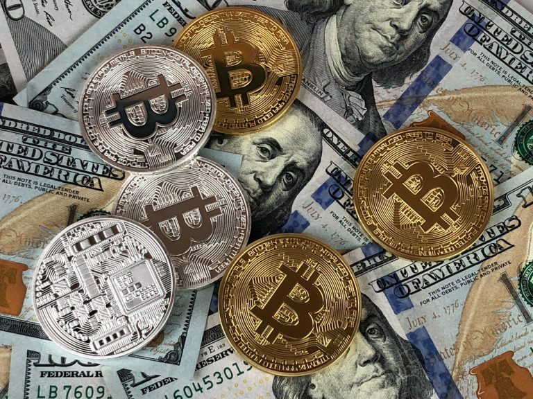 Round silver and gold crypto coins against background of U.S. one-hundred dollar bills