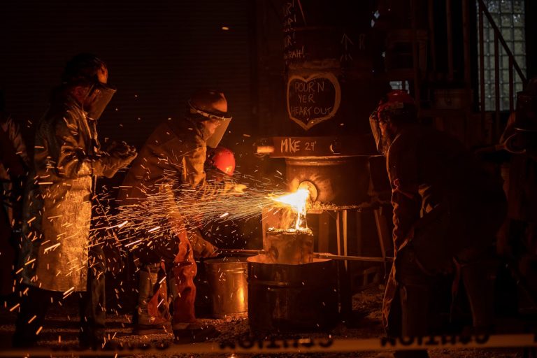 Industrial workers in foundry working with molten metal.