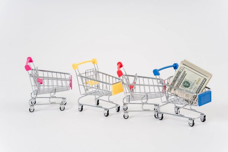 Assorted color mini shopping carts with American dollars in one cart.