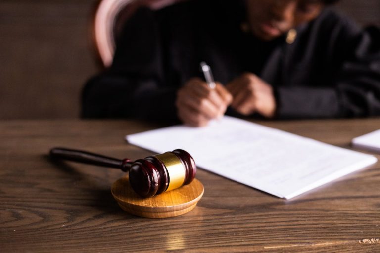 Judge signing papers with gavel in foreground.